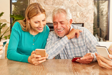 Frau zeigt Senior eine SMS auf dem Smartphone
