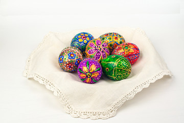 Bright hand-painted Easter eggs on a white embroidered napkin