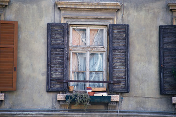 Italian window on the old wall facade with open wooden shabby brown paint shutters