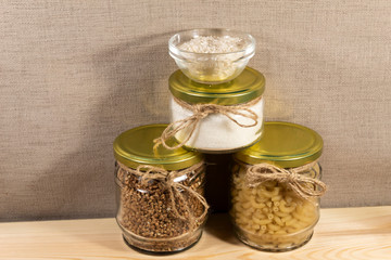 On the board are three cans of pasta, buckwheat and sugar. At the top is a bowl of rice.