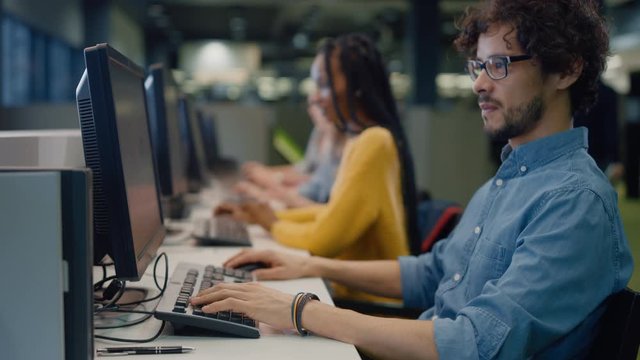 University Library: Bright Boy and Girl using Computers for Class Assignment. Diverse Multi-Ethnic Group of Students Learning, Studying for Exams, Work on Computers, Talk in College Study Room