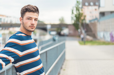 Waist up of dreamful guy. One young beautiful man in the street, outdoor