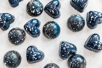 Close-up chocolate candies of blue color with white splashes under stone, top view