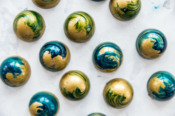 Close-up chocolate candies of blue color with white splashes under stone, top view