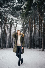 Woman in full growth on background of snowy trees on walk in winter forest