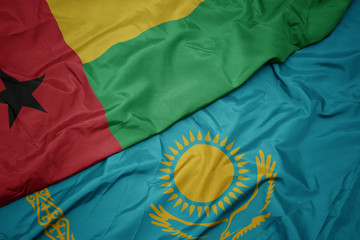 waving colorful flag of kazakhstan and national flag of guinea bissau.