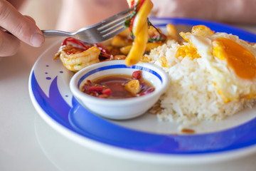 tourist man eating on the beach a Thai dish of rice, eggs and seafood