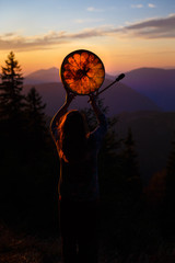 beautiful shamanic girl playing on shaman frame drum in the nature.