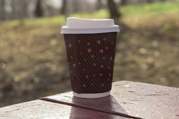 disposable coffee cup with a lid in the park on the blackboard