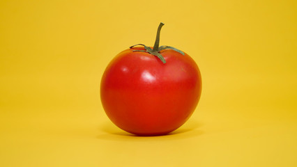 Une tomate rouge sur un arrière plan jaune
