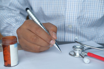 Close up of doctor hand writing prescription.