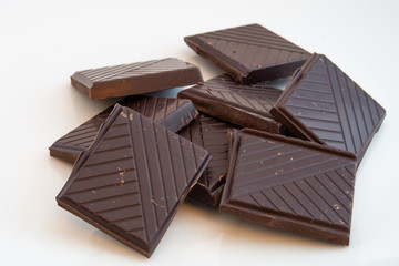 close-up of squares of dark chocolate on a white background