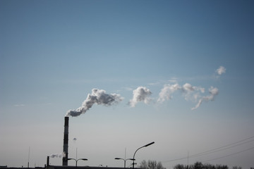 steam smoke coming from a chimney in an industrial zone on the outskirts of a city
