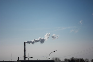 steam smoke coming from a chimney in an industrial zone on the outskirts of a city