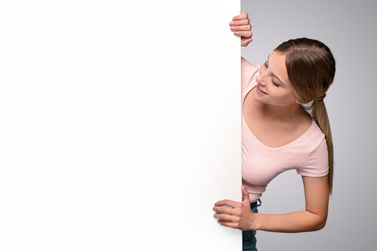 Happy Young Woman Peeking Out From Behind Banner