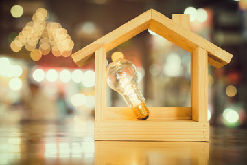 Light bulb with wood house on the table, a symbol for construction, Creative light bulb idea, power energy or business idea concept ecology, loan, mortgage, property or home.