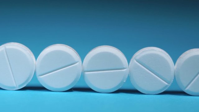 round white tablets in hand, close-up on a blue background with space for text or image. tablets for skin aging