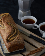 Vegan banana bread with banana on top. loaf cake and coffee. Dark and moody food photography. Selective focus