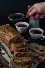 Vegan banana bread with banana on top. loaf cake and coffee. Dark and moody food photography. Selective focus