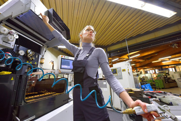 A young woman works as a computerized  numerical control engineer. She is seen at her workplace wearing a blue overall. 