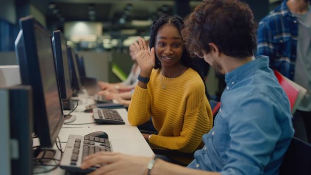 University Library: Bright Black Girl and Smart Hispanic Boy Together Work on Computers, Chat, Discuss Class Assignment, Explain and Advice Each Other. Diverse Group of Students Exam Study Teamwork