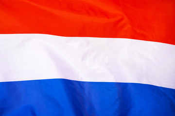 Fabric texture flag of Netherlands. Flag of Netherlands waving in the wind. Netherlands flag is depicted on a sports cloth fabric with many folds. Sport team banner.    