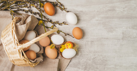 Easter white egg with little chick toys in nest on a grey wooden table, in rustic style. Banner photo.