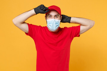 Delivery man in red cap blank t-shirt uniform sterile face mask gloves isolated on yellow background studio Guy employee working courier Service quarantine pandemic coronavirus virus 2019-ncov concept
