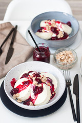 Cottage cheese pancakes with cherry sauce, sour cream and caramelized nuts on white table.