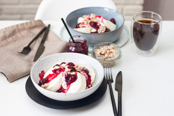 Cottage cheese pancakes with cherry sauce, sour cream and caramelized nuts on white table.