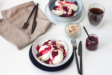 Cottage cheese pancakes with cherry sauce, sour cream and caramelized nuts on white table.