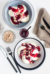 Cottage cheese pancakes with cherry sauce, sour cream and caramelized nuts on white table.