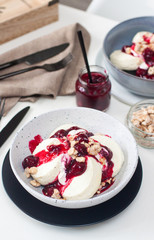 Cottage cheese pancakes with cherry sauce, sour cream and caramelized nuts on white table.