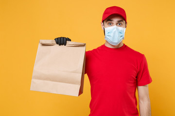 Delivery man employee in red cap blank t-shirt uniform mask glove hold craft paper packet with food...