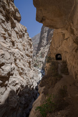 road next to the precipice that runs through natural rock tunnel, parallel to the river in the canyon of the duck, in peru. Vertical