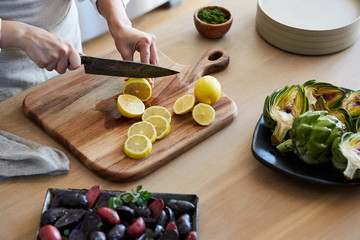 Woman in kitchen slicing lemons for cooking