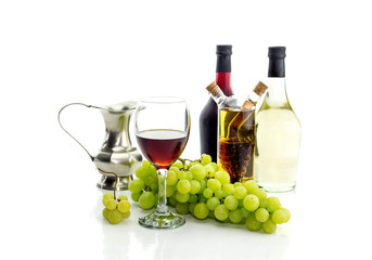 Obraz premium Bottles of wine, pitcher, wine glass and grapes on a white background close-up