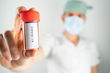 Doctor surgeon with a tube of biological sample infected by Coronavirus with label COVID-19