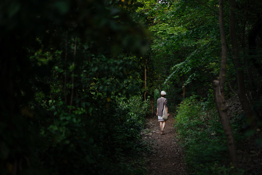 Unrecognizable woman walking in dark forest