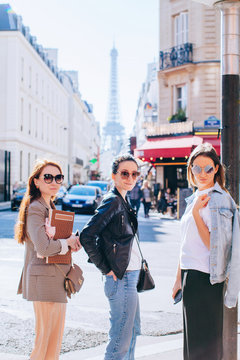 Three girlfriends on the Paris street with view on the Eiffel tower