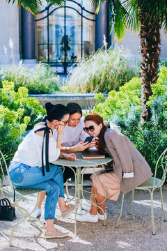 Three friends sitting at the table at the garden and chatting