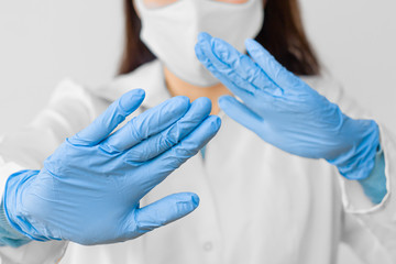 Stop SARS-CoV, SARSCoV, virus 2020 , MERS-CoV ,chinese virus COVID-19. Closeup womans hands in blue medical gloves show STOP sign to illness. Doctor wearing protection face mask against coronavirus.