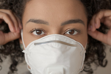 Closeup of adult african american woman putting mask on her face. Action to prevent the spread of...