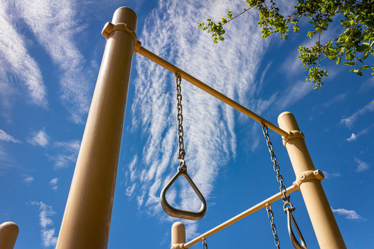 Gymnastics rings at park on sunny day with blue sky