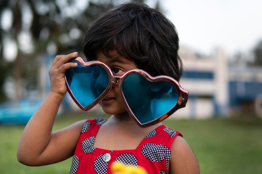 Little girl making fun with sunglasses at outdoors