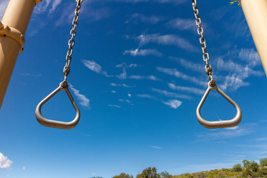 Gymnastics rings at park on sunny day with blue sky