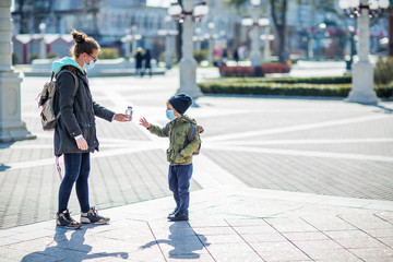 Mother and her son outdoor wearing masks with a bottle of water