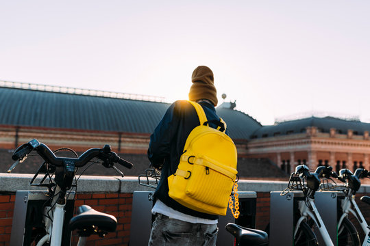 Young asian man picking an urban bicycle from the public parking