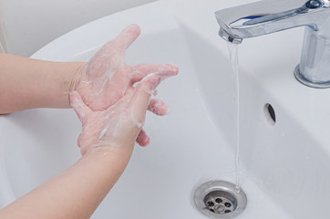 The child washes his hands with soap in the sink under the tap with water. Compliance with...
