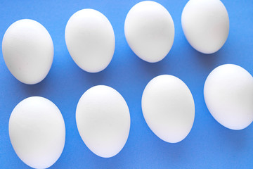 White chicken eggs close-up on a blue background top view. Great Easter